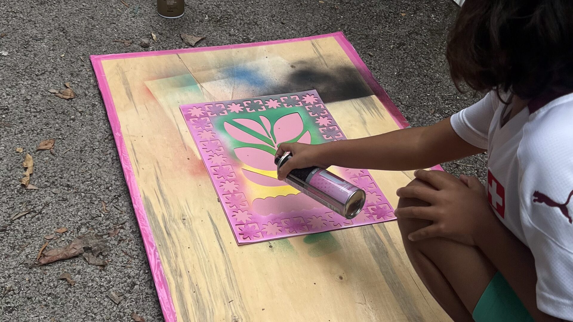 A young person knelt down spray painting artwork