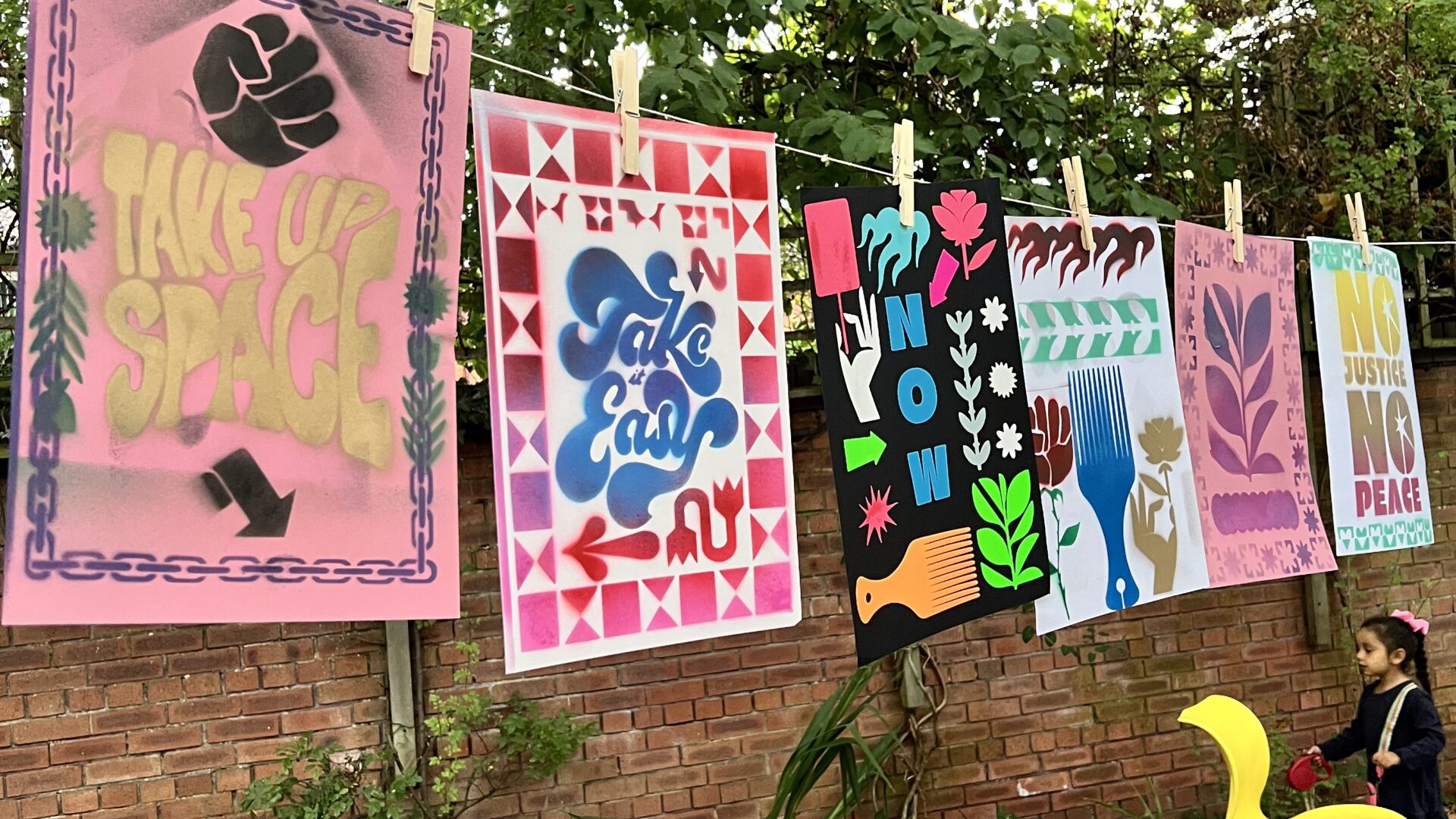 Artwork hanging up on a line, with beanbags and yoga mats beneath them.